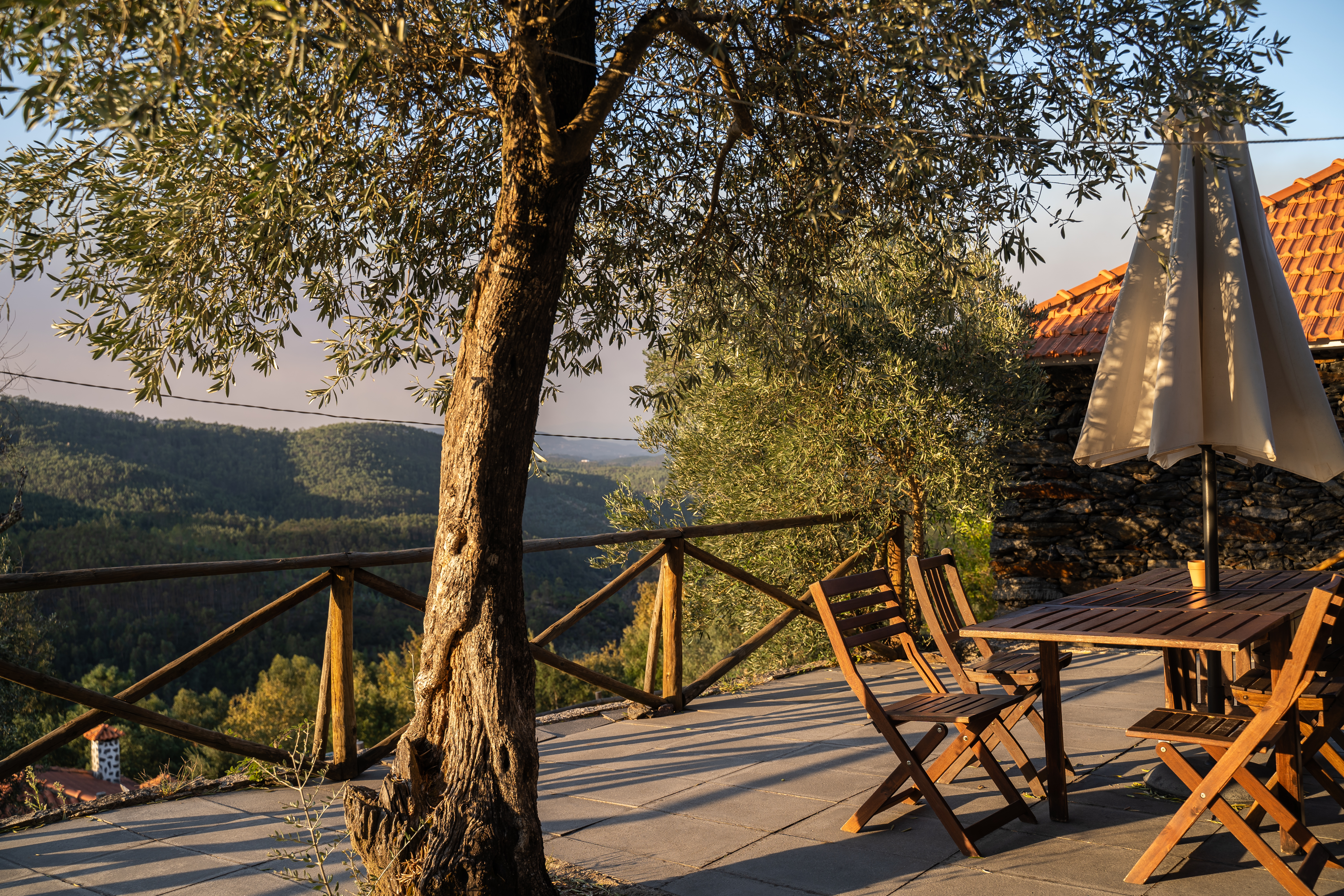 Esplanada com mesa de madeira e vista para o vale